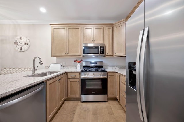 kitchen with stainless steel appliances, a sink, light wood-type flooring, light stone countertops, and crown molding