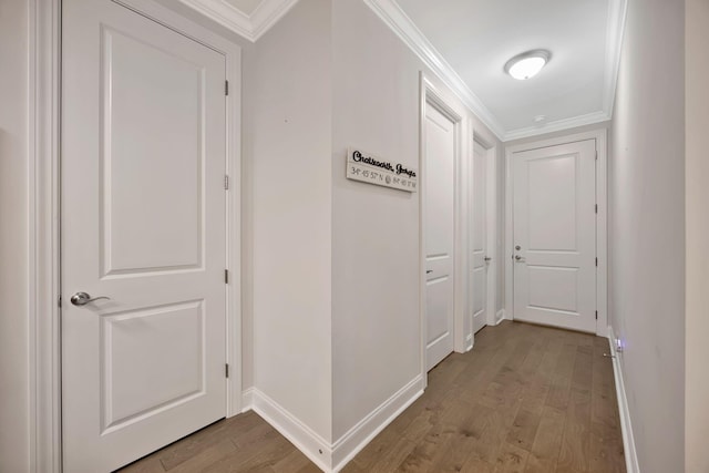 hallway with light wood finished floors, baseboards, and ornamental molding