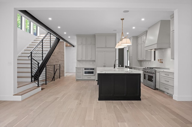 1608 Knickerbocker Ave, Chattanooga, TN 37405 - kitchen featuring appliances with stainless steel finishes, premium range hood, a sink, decorative backsplash, and light wood-style flooring