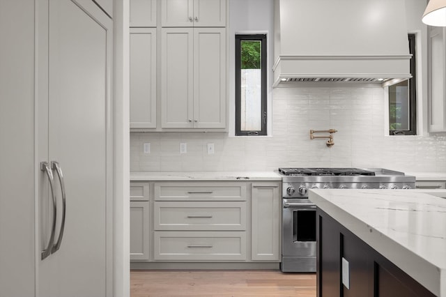 1608 Knickerbocker Ave, Chattanooga, TN 37405 - kitchen featuring high end stainless steel range, custom exhaust hood, decorative backsplash, light stone countertops, and light wood-type flooring