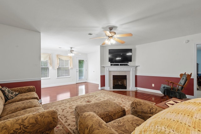 living area featuring wood finished floors, ceiling fan, a fireplace, and baseboards
