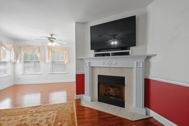 detailed view of wood finished floors, a ceiling fan, and a fireplace