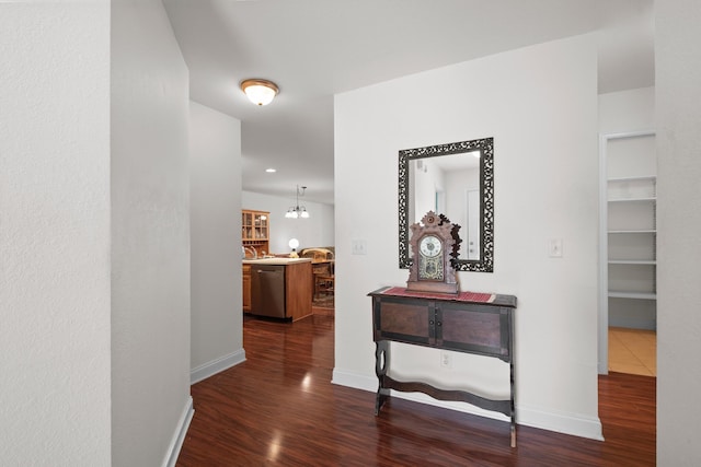corridor with dark wood-style flooring, baseboards, and a chandelier