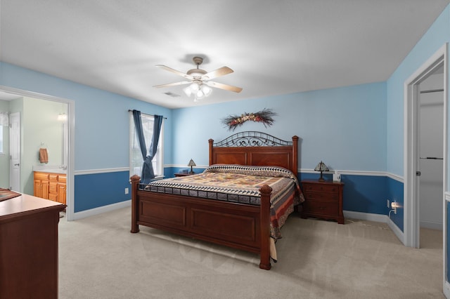 bedroom featuring light colored carpet, baseboards, and ensuite bath