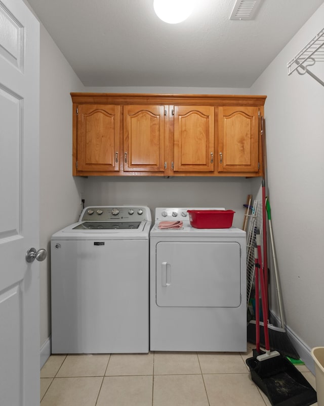 washroom with washer and dryer, cabinet space, light tile patterned floors, and baseboards