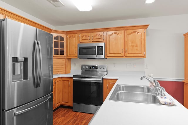 kitchen with stainless steel appliances, a sink, dark wood-style flooring, light countertops, and recessed lighting