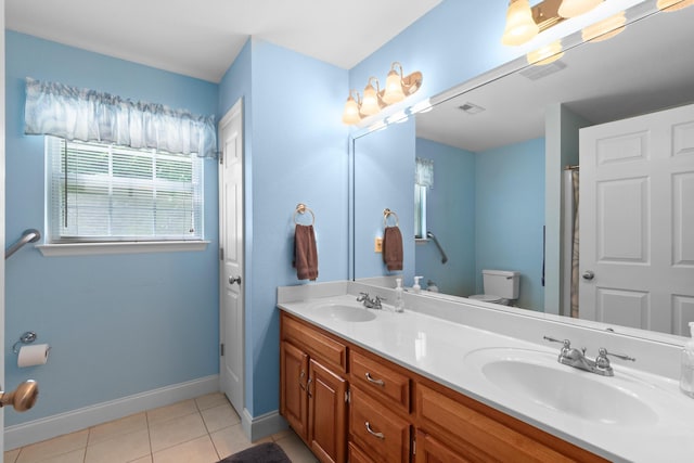 full bath with baseboards, double vanity, tile patterned floors, and toilet