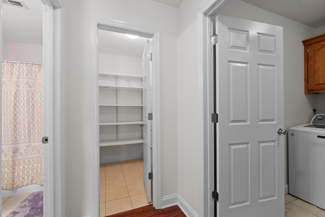 laundry room featuring washer / clothes dryer, cabinet space, and light tile patterned flooring
