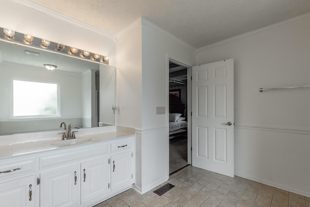 bathroom with a wainscoted wall, vanity, tile patterned flooring, a textured ceiling, and ornamental molding