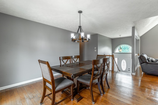 dining room with a chandelier, a textured ceiling, hardwood / wood-style floors, and baseboards
