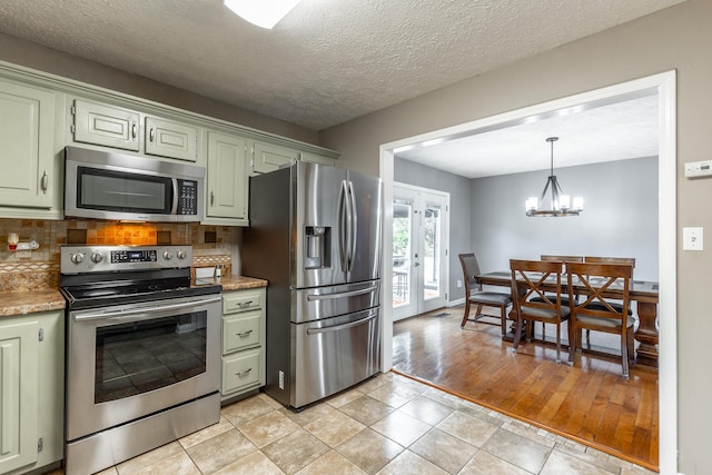 kitchen featuring appliances with stainless steel finishes, decorative backsplash, a chandelier, and pendant lighting