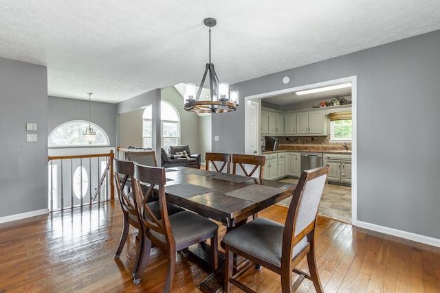 dining area featuring a chandelier, baseboards, hardwood / wood-style flooring, and a textured ceiling