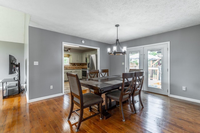 dining area featuring wood-type flooring, baseboards, a chandelier, and a textured ceiling