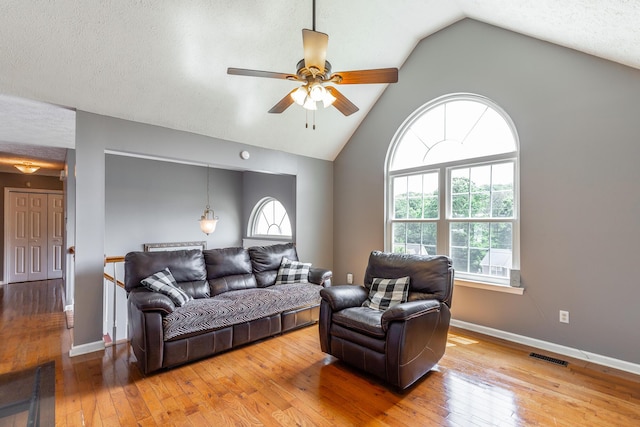 living area with plenty of natural light, a ceiling fan, wood-type flooring, and lofted ceiling