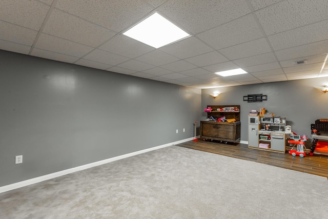 finished basement featuring a paneled ceiling, baseboards, and carpet floors