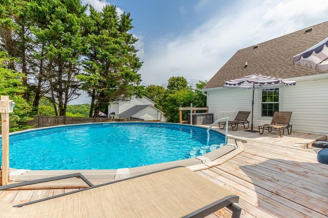 view of swimming pool with a wooden deck and fence