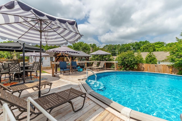 view of swimming pool featuring outdoor dining space, a deck, and a fenced backyard