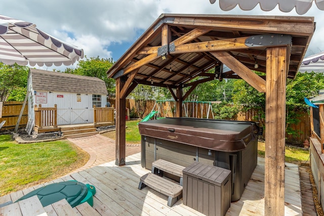 deck with a hot tub, a fenced backyard, a gazebo, a shed, and an outbuilding