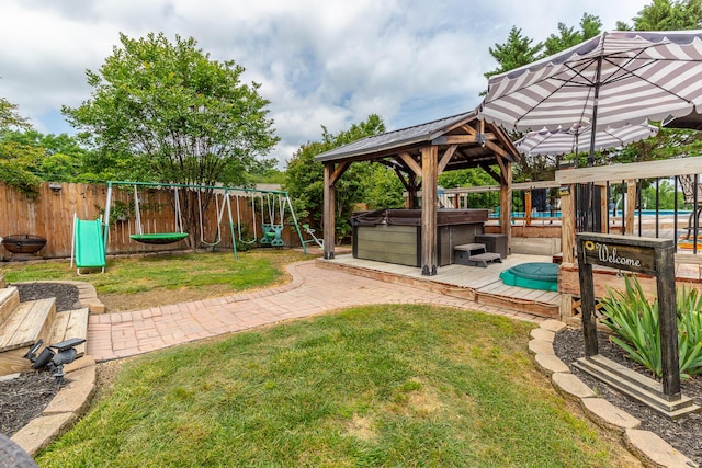 view of yard featuring a hot tub, a playground, a gazebo, and a wooden deck