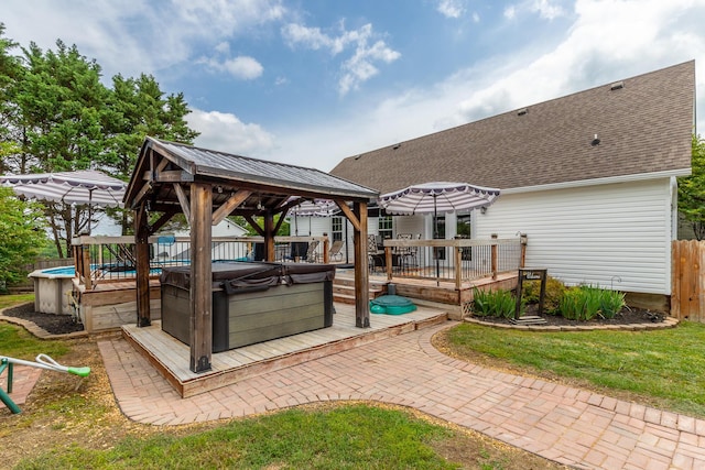 view of patio / terrace featuring a covered hot tub, a gazebo, a deck, fence, and an outdoor pool