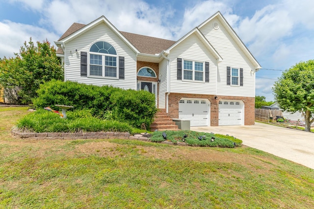 raised ranch featuring brick siding, a garage, concrete driveway, and a front yard