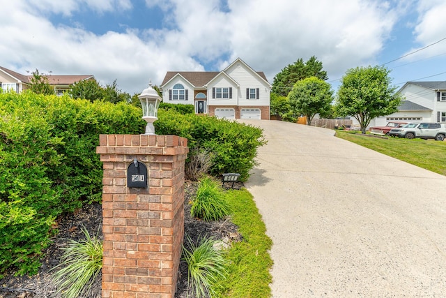 bi-level home featuring a garage, concrete driveway, and fence