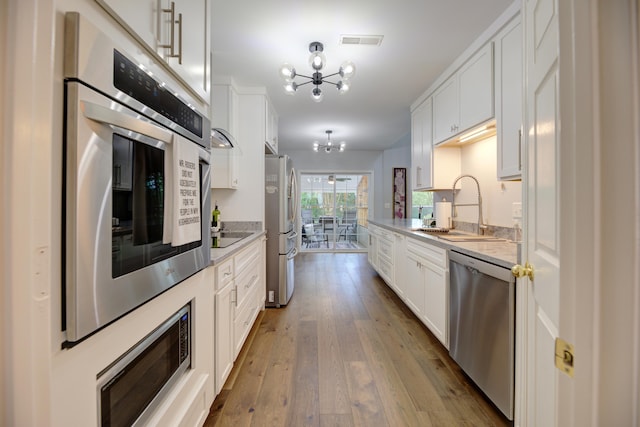 7830 Legacy Park Ct, Chattanooga, TN 37421 - kitchen featuring appliances with stainless steel finishes, a chandelier, a sink, hardwood / wood-style floors, and white cabinets