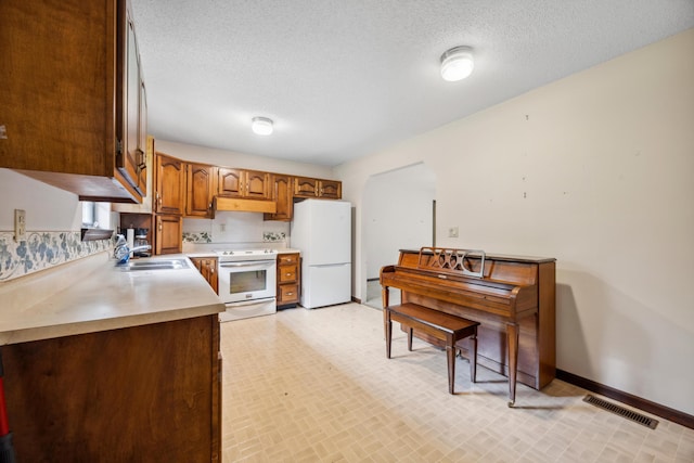 2126 Millard Rd, Soddy Daisy, TN 37379 - kitchen featuring white appliances, a sink, under cabinet range hood, light countertops, and baseboards