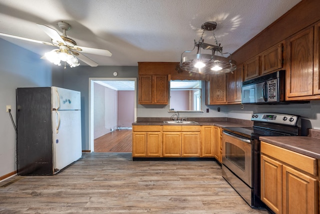 1002 Gillespie Rd, Chattanooga, TN 37411 - kitchen with stainless steel electric stove, black microwave, freestanding refrigerator, dark countertops, and light wood-type flooring