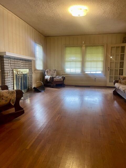 4908 13th Ave, Chattanooga, TN 37407 - living area featuring a textured ceiling, a brick fireplace, wood finished floors, and wood walls
