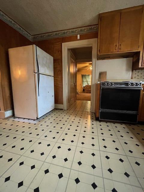 4908 13th Ave, Chattanooga, TN 37407 - kitchen with range, freestanding refrigerator, under cabinet range hood, a textured ceiling, and brown cabinetry