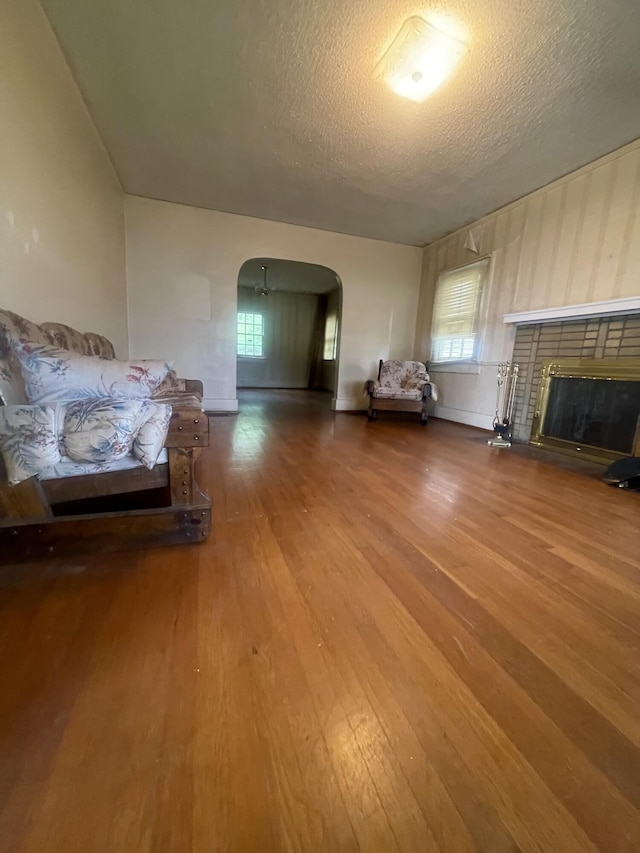 4908 13th Ave, Chattanooga, TN 37407 - living room featuring wood finished floors, arched walkways, a textured ceiling, and a brick fireplace