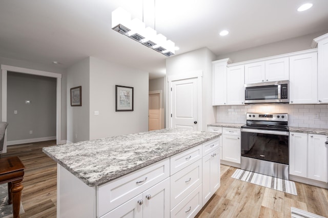 8647 Kensley Ln, Hixson, TN 37343 - kitchen with stainless steel appliances, light wood-style flooring, a center island, tasteful backsplash, and recessed lighting