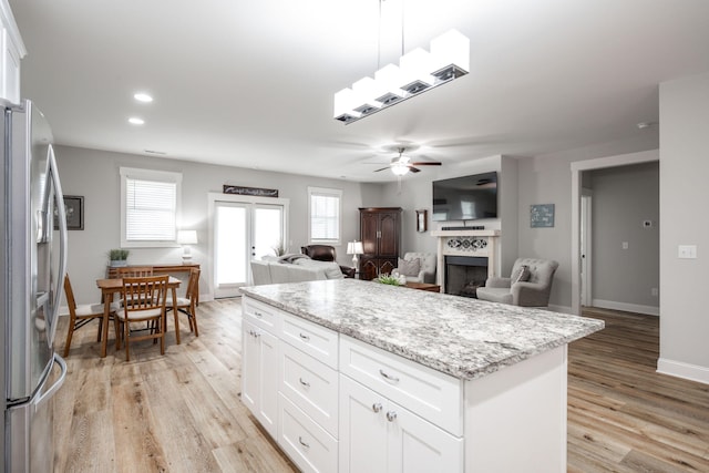 8647 Kensley Ln, Hixson, TN 37343 - kitchen featuring stainless steel fridge with ice dispenser, ceiling fan, a fireplace, light wood-type flooring, and white cabinetry
