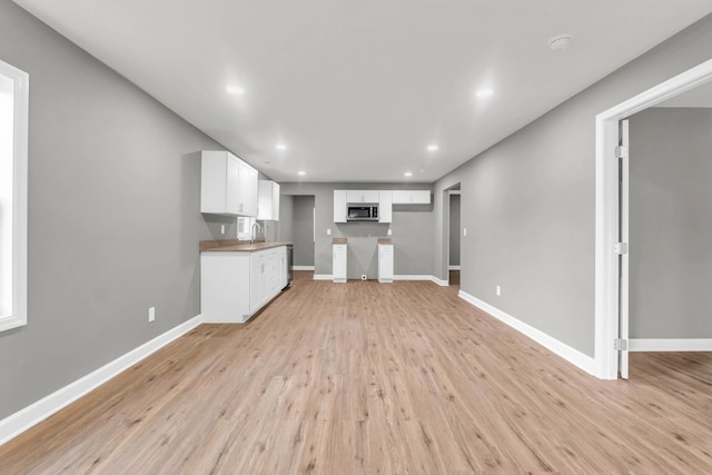 1904 Sharp St, Chattanooga, TN 37404 - kitchen featuring stainless steel microwave, a sink, light wood-type flooring, white cabinetry, and baseboards