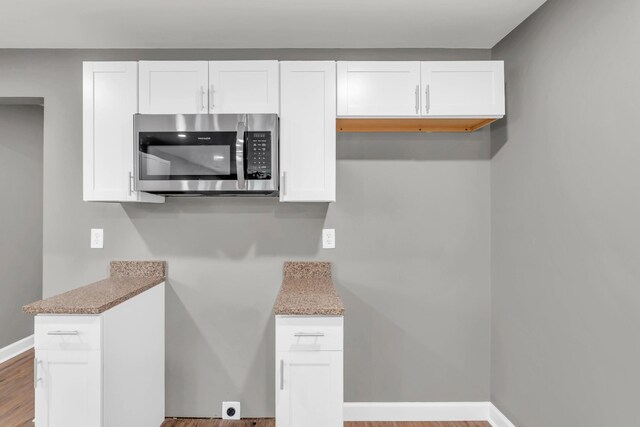 1904 Sharp St, Chattanooga, TN 37404 - kitchen with stainless steel microwave, white cabinets, wood finished floors, and baseboards