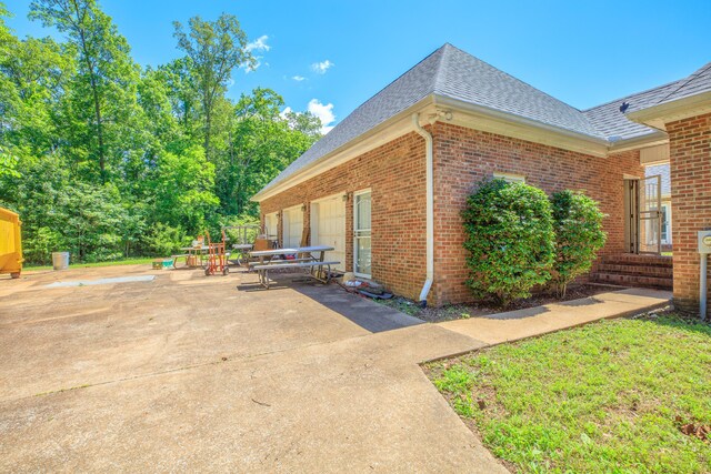 7902 Ooltewah Georgetown Rd, Ooltewah, TN 37363 - view of home's exterior featuring roof with shingles, brick siding, and a patio area