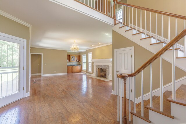 7902 Ooltewah Georgetown Rd, Ooltewah, TN 37363 - unfurnished living room featuring ornamental molding, a chandelier, stairs, baseboards, and wood finished floors