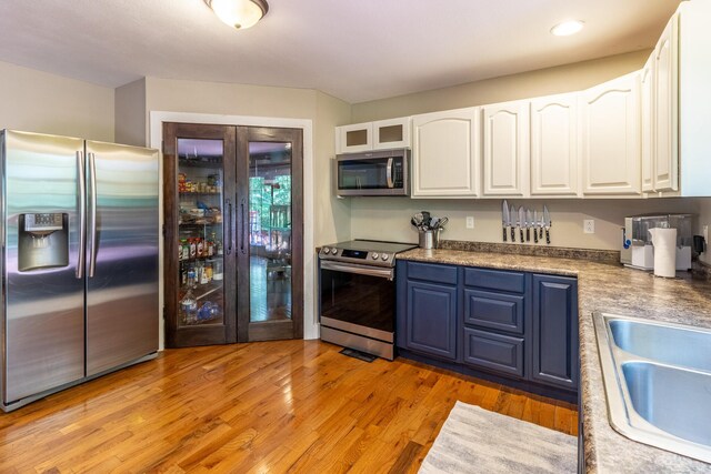 2217 Sr 399, Palmer, TN 37365 - kitchen with appliances with stainless steel finishes, white cabinets, a sink, blue cabinetry, and light wood-style floors