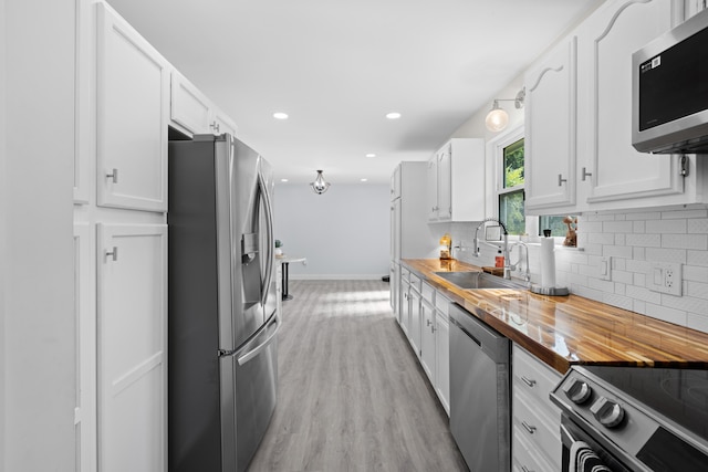 9503 Weidner Ln, Ooltewah, TN 37363 - kitchen featuring appliances with stainless steel finishes, a sink, butcher block counters, tasteful backsplash, and white cabinets