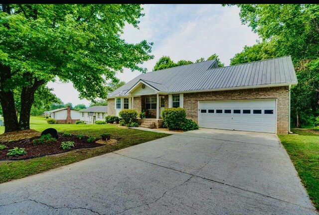 8719 Glenaire Dr, Chattanooga, TN 37416 - ranch-style house with driveway, a front lawn, a garage, and a metal roof