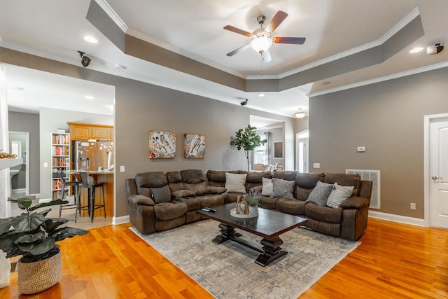 9923 Sims Harris Rd, Ooltewah, TN 37363 - living room featuring a ceiling fan, light wood-style flooring, baseboards, a tray ceiling, and ornamental molding