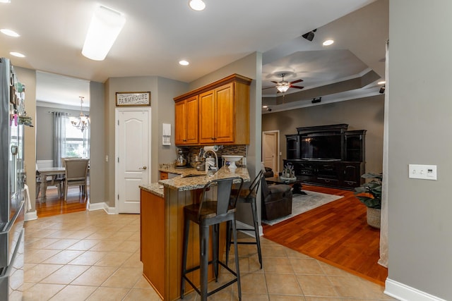 9923 Sims Harris Rd, Ooltewah, TN 37363 - kitchen with a sink, light tile patterned flooring, light stone countertops, a breakfast bar, and a peninsula