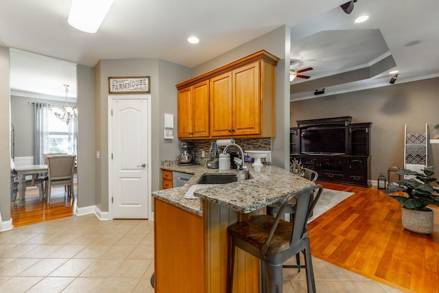 9923 Sims Harris Rd, Ooltewah, TN 37363 - kitchen featuring a sink, a chandelier, light stone counters, brown cabinets, and crown molding