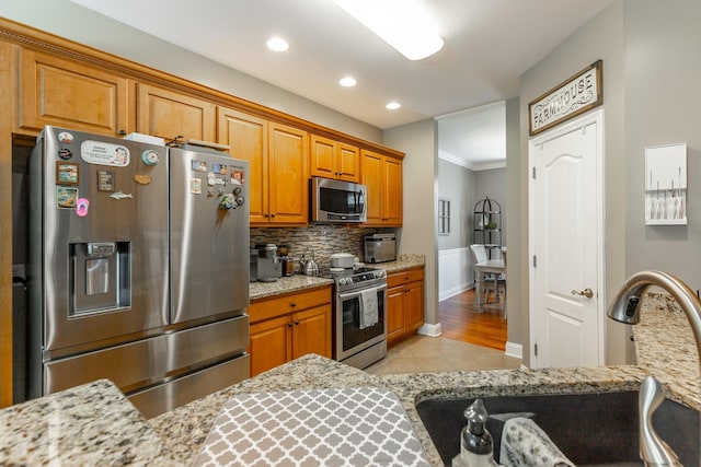 9923 Sims Harris Rd, Ooltewah, TN 37363 - kitchen with stainless steel appliances, decorative backsplash, brown cabinetry, light tile patterned floors, and light stone counters