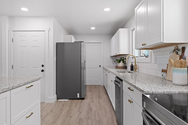 1795 Dowdy Rd, Cleveland, TN 37323 - kitchen featuring appliances with stainless steel finishes, a sink, light wood finished floors, white cabinetry, and decorative backsplash