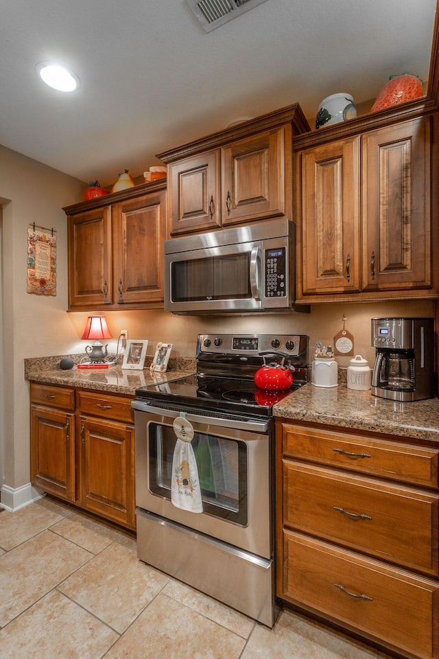 169 Southern Dr, Ringgold, GA 30736 - kitchen with stainless steel appliances, brown cabinets, light tile patterned flooring, stone counters, and baseboards