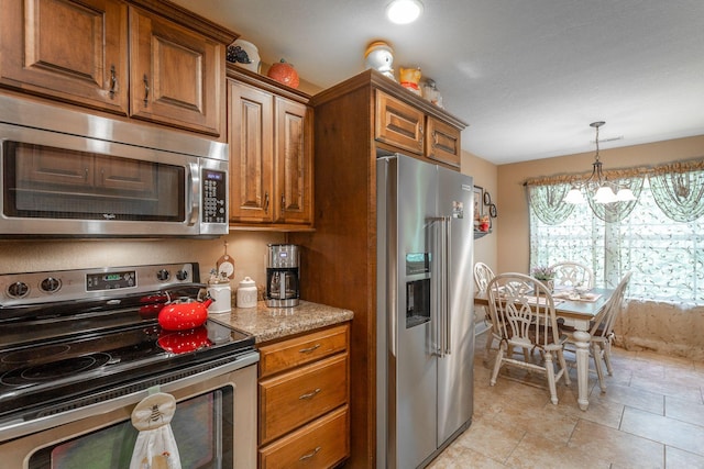 169 Southern Dr, Ringgold, GA 30736 - kitchen featuring stainless steel appliances, brown cabinets, light stone counters, a chandelier, and decorative light fixtures