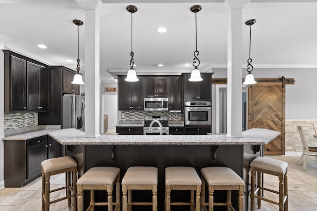 2904 Reflection Ln, Ooltewah, TN 37363 - kitchen featuring stainless steel appliances, crown molding, decorative backsplash, light stone countertops, and a kitchen breakfast bar