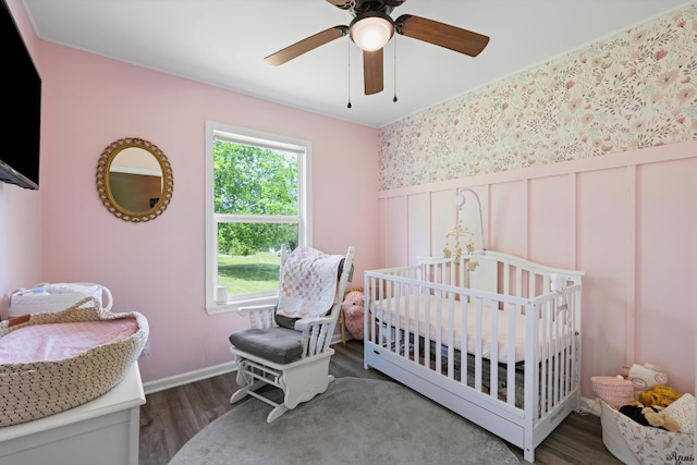334 Kay Conley Rd, Rock Spring, GA 30739 - bedroom featuring wainscoting, wood finished floors, a decorative wall, a ceiling fan, and a crib